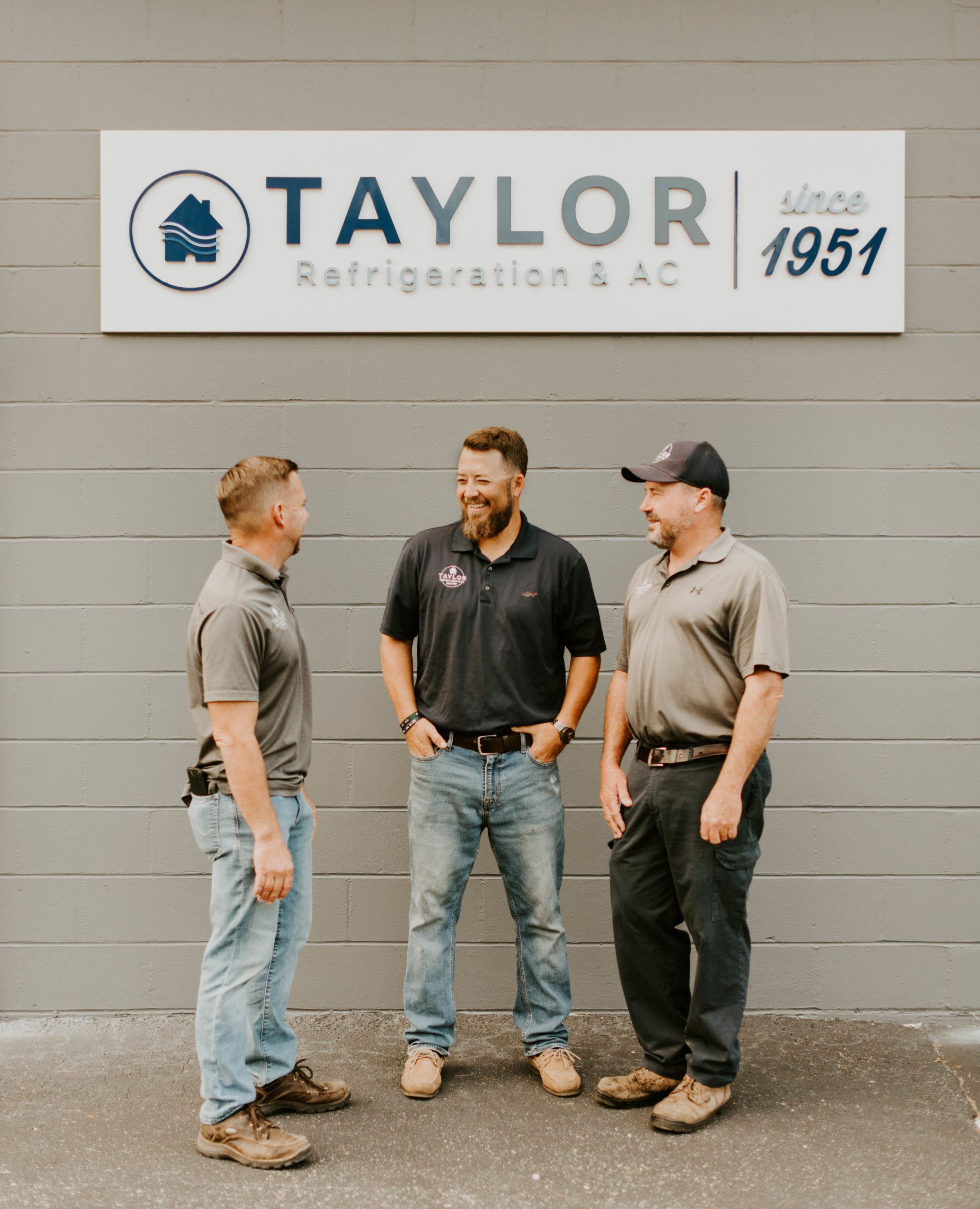 Ben, Luke and Mike laughing by a Taylor Ref sign